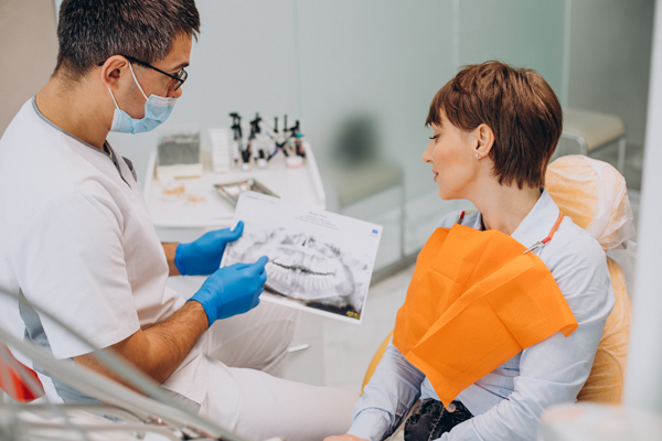 Dentist showing patient dental X-ray.
