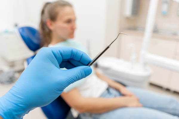 Gloved hand holding dental tool.